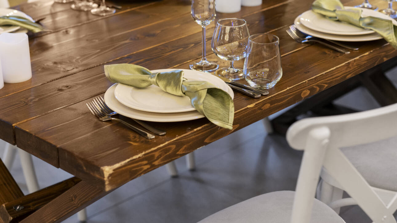 Table à manger en bois massif dressée avec vaisselle élégante et chaises blanches dans un intérieur contemporain.