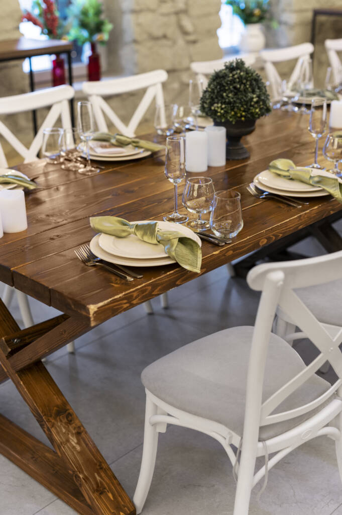 Table à manger en bois massif dressée avec vaisselle élégante et chaises blanches dans un intérieur contemporain.